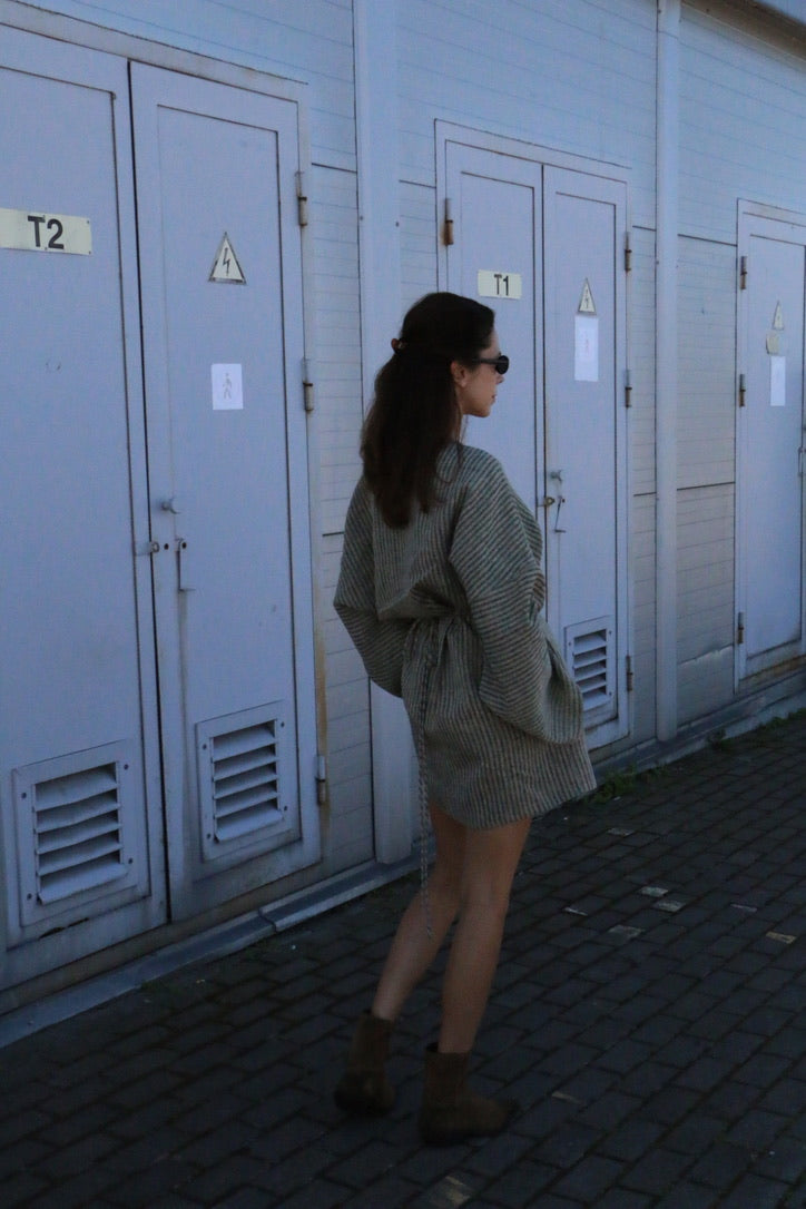 Woman wearing a natural linen kimono mini dress with wrap waist, oversized sleeves and hidden pockets.