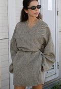 Woman wearing a natural linen kimono mini dress with wrap waist, oversized sleeves and hidden pockets.