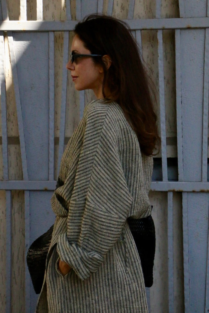 Woman wearing a striped linen kimono wrap dress with oversized sleeves and an adjustable waist tie.