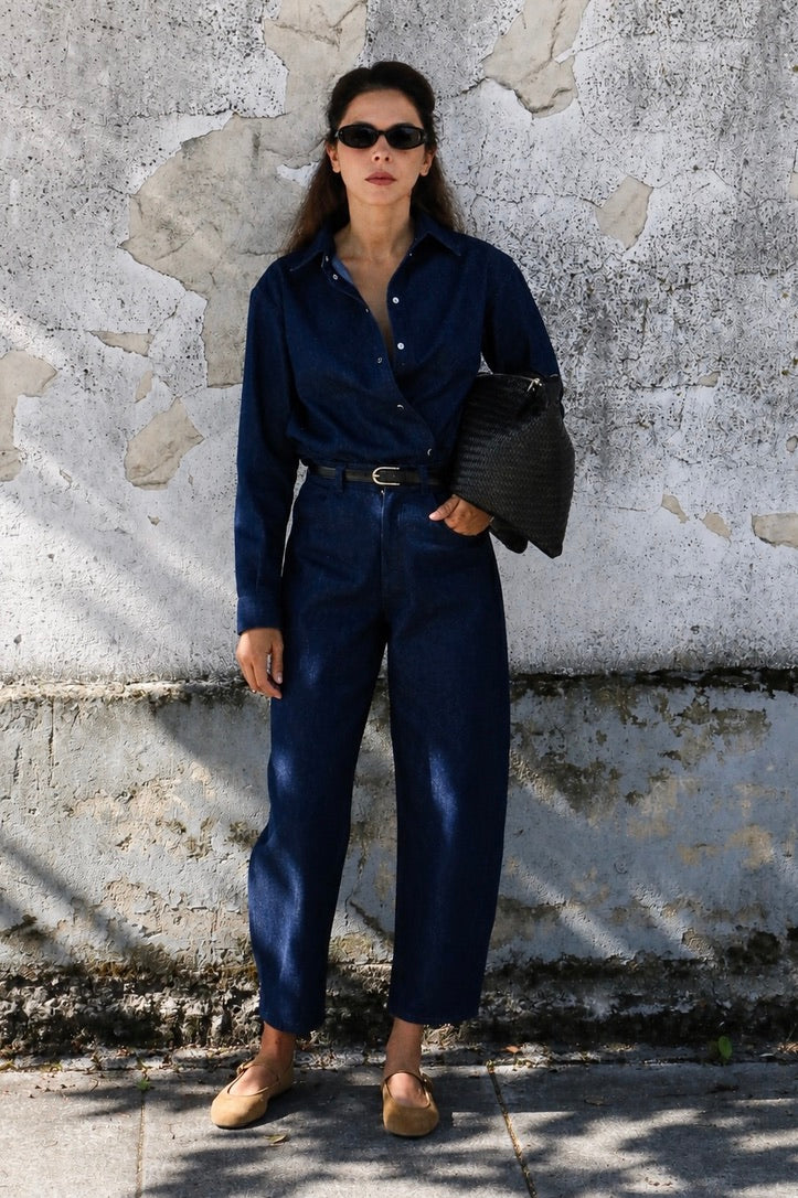 Woman wearing dark blue high-waisted barrel leg jeans with a matching denim shirt.