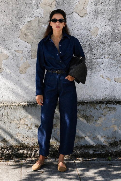 Woman wearing dark blue high-waisted barrel leg jeans with a matching denim shirt.